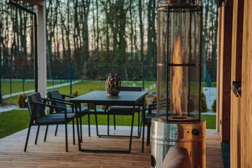 a grill on a deck with a table and chairs at Forrestia - osada turystyczna in Czaplinek