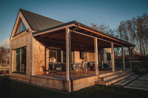 a wooden cabin with a deck with tables and chairs at Forrestia - osada turystyczna in Czaplinek