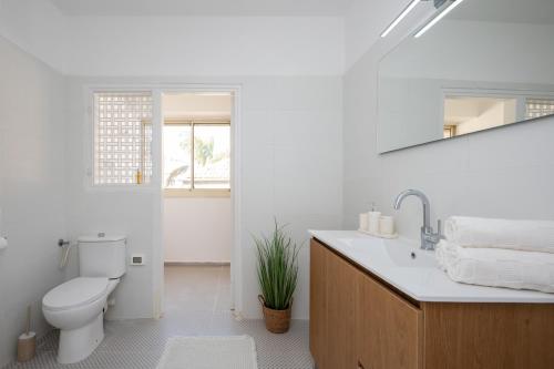 a white bathroom with a toilet and a sink at R26-Boutique in Zikhron Ya'akov