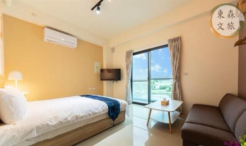 a bedroom with a bed and a couch and a window at 不想回家民宿-免費停車-寵物友善-無門禁24小時進出-東森文旅-包棟優惠中 in Yuanshan
