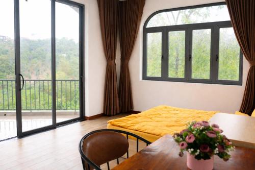 a room with a bed and a table and windows at B'lao Eco Lodge in Bảo Lộc