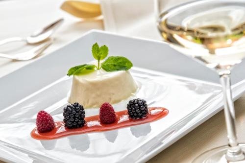 a dessert on a white plate with strawberries and blackberries at Hotel Armin in Selva di Val Gardena