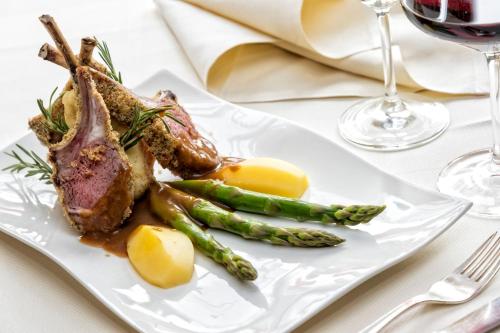 a white plate with a piece of meat and asparagus at Hotel Armin in Selva di Val Gardena