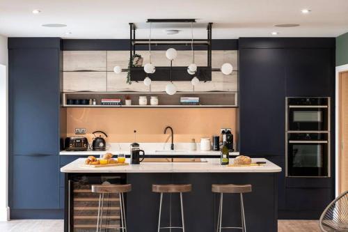 a kitchen with a counter with bar stools in it at Brockview House - Eco 4 bed in Holcombe