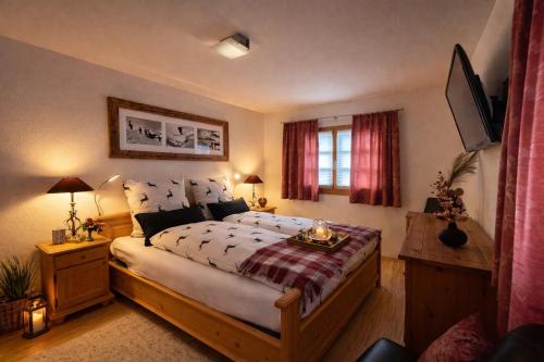 a bedroom with a large bed and a television at Laax Cozy Apartment - Ski Bus - Fireplace in Laax