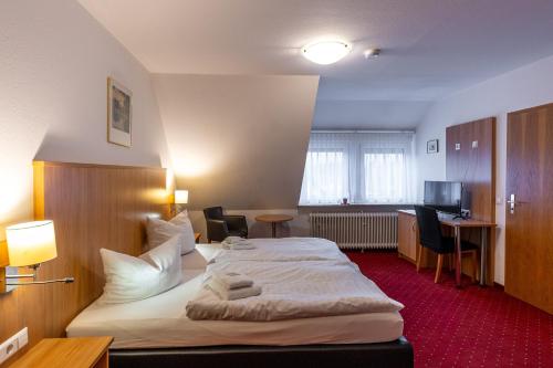a hotel room with a large bed and a desk at Pension Krone in Schwäbisch Gmünd