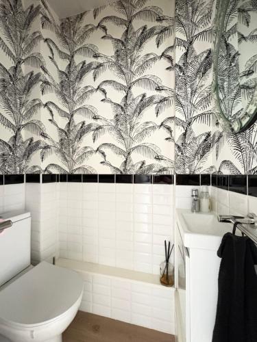 a bathroom with a white toilet and a black and white wallpaper at Nuit D'or - Cape Champagne - Séjour & Pro in Épernay