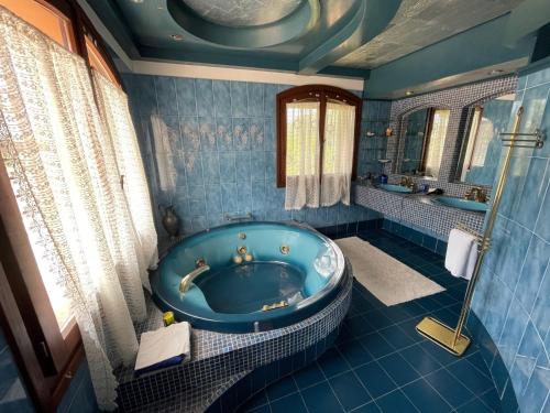 a blue bathroom with a tub and a mirror at Villa Lorivita in Bevazzana
