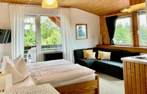 ein Wohnzimmer mit Couch und ein Wohnzimmer mit Fenstern in der Unterkunft Hotel Barbara in Warmensteinach