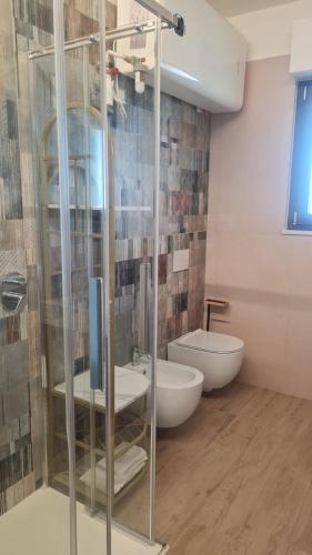 a bathroom with a glass shower with a sink and a toilet at Civitas Locanda in Ghedi
