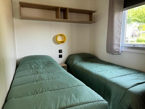 two green beds in a small room with a window at Altamira Camping in Queveda