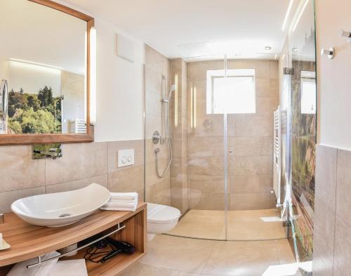 a bathroom with a shower and a sink and a toilet at Seehotel Sparer in Appiano sulla Strada del Vino