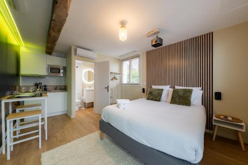 a bedroom with a white bed and a kitchen at Air Nomad • Stockholm in Valenciennes