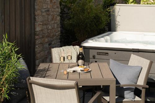 a table and chairs with a bottle of wine and a sink at Hill View House - Cookswood in Holcombe