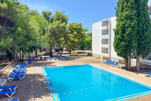 a swimming pool with lounge chairs and a building at hotel depandance Imperial Green by GLOBTOUR in Vodice