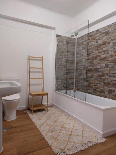 a bathroom with a tub and a toilet and a chair at Praia Dona Ana - Bedrooms in shared apartment in Lagos