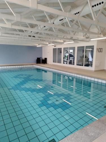 a large swimming pool with a blue tile floor at Hotel Tannishus in Bindslev