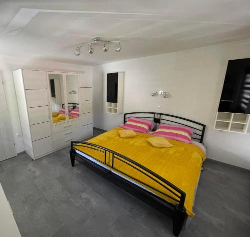 a bedroom with a bed with yellow sheets and pink pillows at Apartma Devs in Kranjska Gora