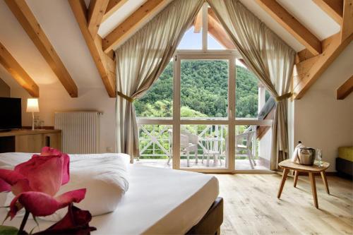 a bedroom with a bed and a large window at Seehotel Sparer in Appiano sulla Strada del Vino