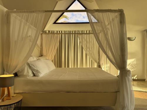 a bedroom with a canopy bed with a window at Sunset View by JuMa in Rivière Noire