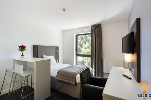 a hotel room with a bed and a desk and a window at Adonis Dijon Maison Internationale in Dijon