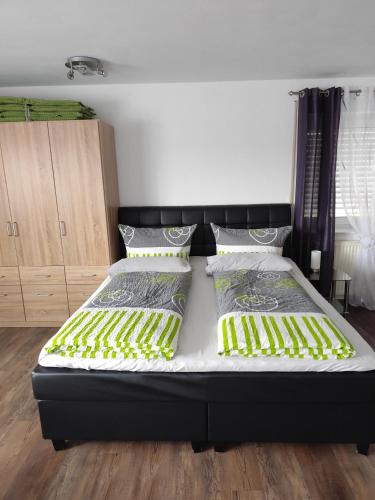 a bedroom with a black bed with yellow and green sheets at Haus Nuhn in Bad Wildungen