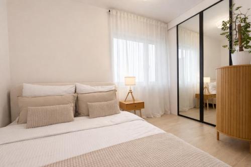 a white bedroom with a large bed and a mirror at BONA Apartment in Świecie