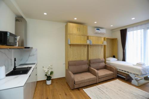 a room with a bed and a chair and a kitchen at La Dimora Azzurra in Vlorë