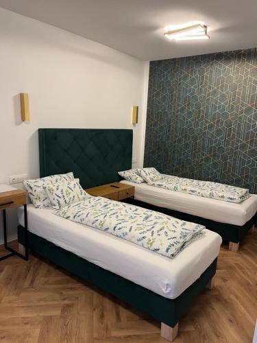 two twin beds in a room with a wall at Jancsó Apartman in Dunaföldvár