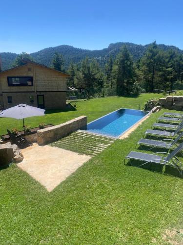 a backyard with a swimming pool with chairs and an umbrella at La Torre d' Espinalbet in Castellar del Riu