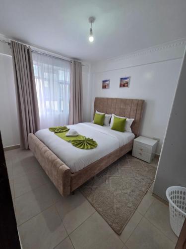 a bedroom with a large bed with green pillows at Waridi Homes One-bedroom Naivegas Apartment in Naivasha