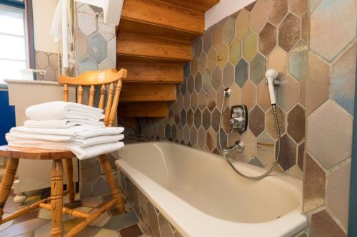 a bath tub in a bathroom with a chair and towels at Hansen Hof 1 in Tinnum