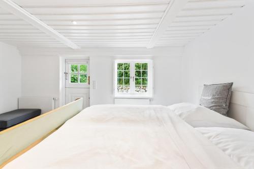 a white bedroom with a large bed and two windows at Carolinen Hof 1 in Tinnum