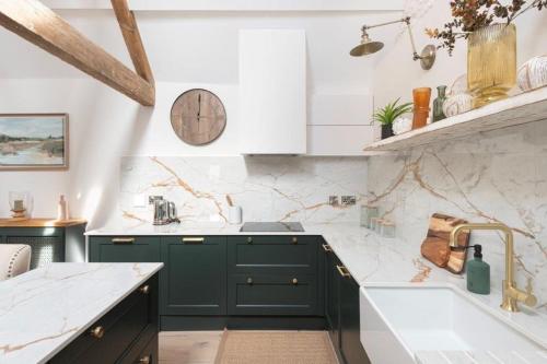 a kitchen with green cabinets and a clock on the wall at The Foaling Box at Lanhill in Oakhill