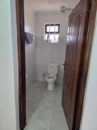 a bathroom with a toilet and a window and a door at Waridi Homes-2 BR Naivegas Apartments, Naivasha in Munyu