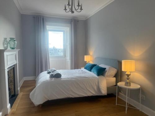 a bedroom with a bed with two lamps and a fireplace at Murrayfield Gem in Edinburgh