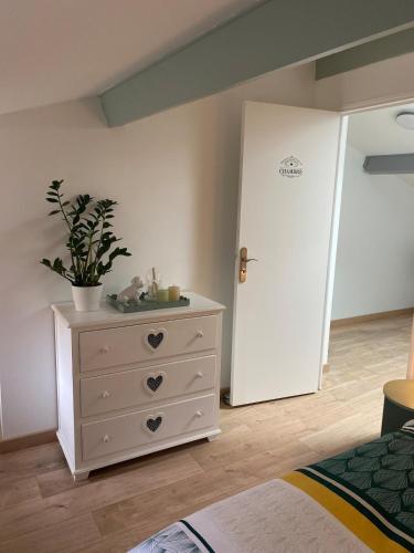a bedroom with a white door and a dresser with a plant at Petite maison de village in Ancerville