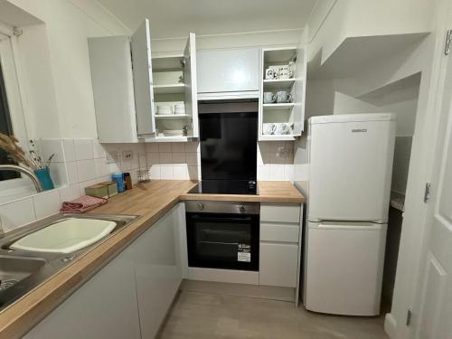 a white kitchen with a sink and a refrigerator at Comfy, king bed families & Contractors welcome in St. Ives