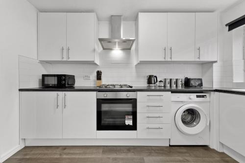 a kitchen with white cabinets and a washing machine at 4 Bedroom Fully Furnished House - Longer Stay Offers - Contractor Digs - NEW in Crawley