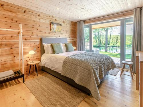a bedroom with a bed and a wooden wall at 3 Bed in Cullompton oc-96118 in Willand