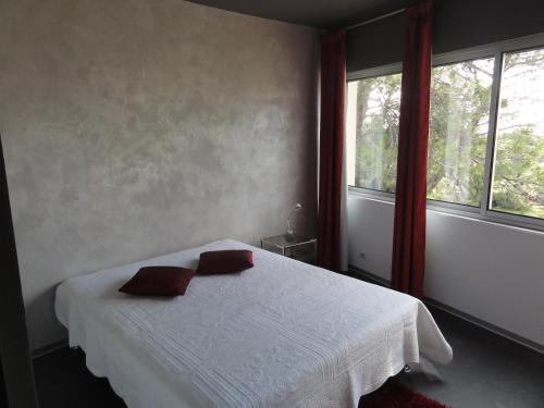 a bedroom with a white bed with two pillows on it at Mahero in Nîmes