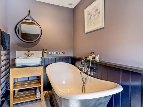a bathroom with a tub and a sink and a mirror at 4 Bed in Brecon oc-90596 in Bwlch