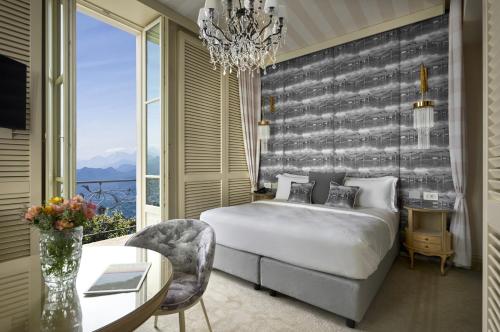 a bedroom with a bed and a table and a chandelier at Nuvole Garden Hotel in Brunate