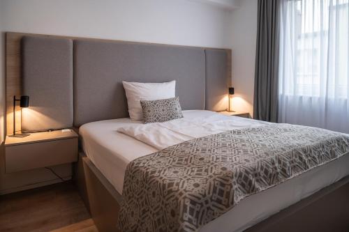 a bedroom with a large bed with two lamps at Aparthotel Cosy in Stuttgart