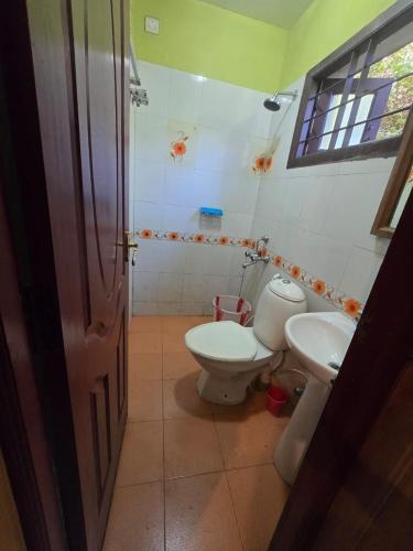 a bathroom with a toilet and a sink at Padayappa Residency in Kodaikānāl