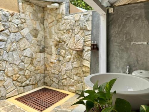 a bathroom with a tub and a stone wall at Ecoya Riverside Resort in Balapitiya