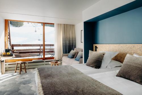 a bedroom with a bed and a blue wall at La Cachette, Friendly Hotel & Spa in Arc 1600