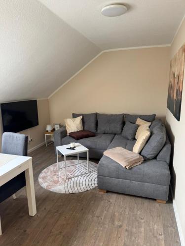 a living room with a gray couch and a table at Eifelnest Stadtkyll in Stadtkyll