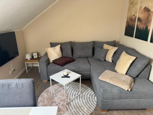 a living room with a gray couch and a table at Eifelnest Stadtkyll in Stadtkyll