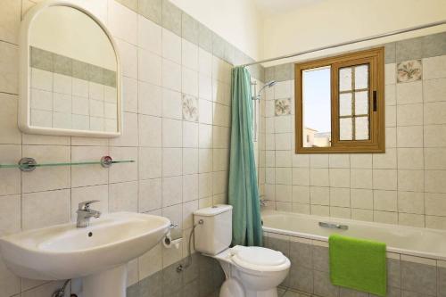 a bathroom with a toilet and a sink and a mirror at Villa Katina by Villa Plus in Peyia
